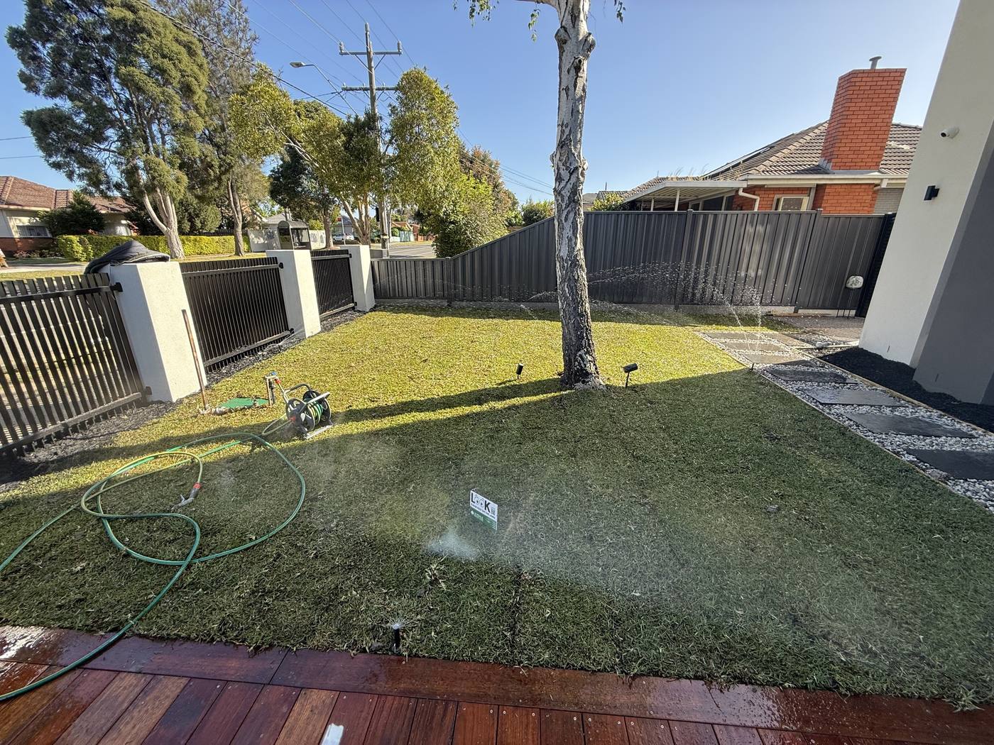 A manicured lawn with pop-ups running alongside decking